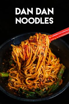 the noodles are being cooked in a pan with chopsticks and sauce on top