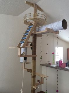 a cat tree that is in the middle of a room with lots of things hanging from it