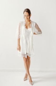 Made in a unique delicate white french lace design, the Lara Lace Robe is the perfect gift for the bride-to-be on her wedding day. Featuring scalloped lace edges along the neckline, hem and sleeve cuffs, this robe exudes old-world elegance. The body of the Lara Robe is fully lined to provide our brides the coverage they need. A slip dress is not required for under this robe, but if you're in search of one we recommend our 'Date Night' Slip Dress. Material: French lace with body liningSleeve: 3/4 Lace Dress With Lace Cuffs For Wedding Night, Feminine Scalloped Lace For Wedding, Feminine White Scalloped Lace, White Scalloped Lace Dress For Wedding Night, Elegant Lace Trim Dress For Ceremony, Feminine Lace Dress With Lace Bodice For Weddings, Feminine Lace Bodice Dress For Wedding, Feminine Lace Bodice For Wedding, Feminine Wedding Lace With Lace Bodice