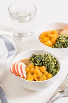 two bowls filled with different types of food next to a glass of water and silverware