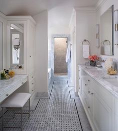 a bathroom with white cabinets and marble counter tops