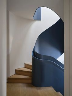 a spiral staircase in a house with white walls and wood floors