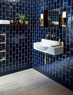 a blue tiled bathroom with gold fixtures and mirrors on the wall, along with a white sink