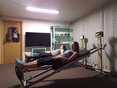 two people laying on exercise equipment in a gym