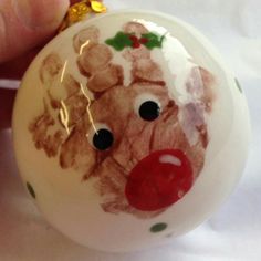 a hand holding a christmas ornament with a reindeer on it's face