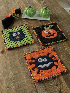 four halloween coasters on a wooden table with pumpkins and jack - o'- lanterns