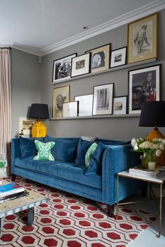 a living room filled with blue couches and pictures on the wall above each sofa