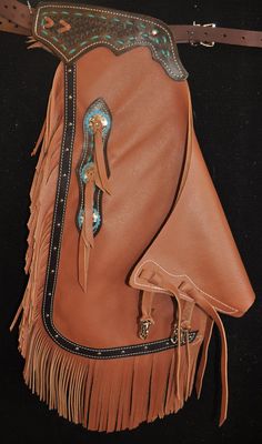 a brown leather purse with fringes and beads on the bottom half, sitting on a black surface