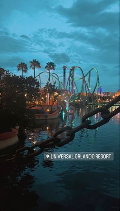 an amusement park at night with boats and roller coasters