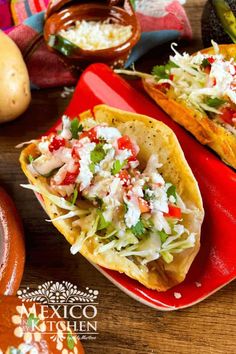 three tacos are sitting on a red plate next to other mexican foods and condiments