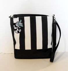 DarksideBags studio offers: A medium-sized over-the-shoulder handbag, made of black synthetic leather and striped velour fabric. The front of the bag is decorated with an applique with the motif from the movie Beetlejuice. Inside, the handbag is finished with smooth alcantara and has two divided slip pockets. The strap is mounted on carabiners. Bag for every season.  Great gift idea! Travel Tote Shoulder Bag With Striped Lining, Trendy Striped Bag With Adjustable Strap, Striped Rectangular Shoulder Bag With Adjustable Strap, Trendy Striped Rectangular Bag, Black Bucket Bag With Zipper For School, Black Bucket Bag With Zipper Closure For School, Striped Tote Shoulder Bag With Striped Lining, Everyday Tote Shoulder Bag With Striped Lining, Tote Shoulder Bag With Striped Lining