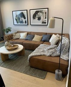 a living room with couches, tables and pictures on the wall above them in front of a window