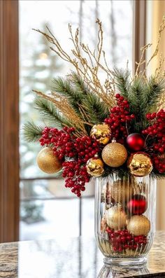 a vase filled with ornaments and greenery on top of a table