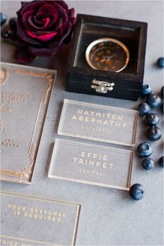 some business cards and a watch on a table with blueberries in front of them