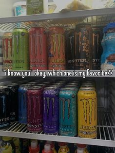 an assortment of monster energy drinks on display in a refrigerator with other beverages behind it