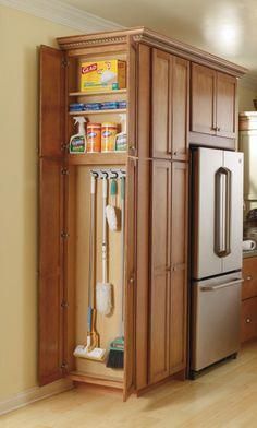 an organized kitchen with wooden cabinets and stainless steel appliances in the corner, along with cleaning supplies