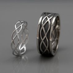 two wedding bands made out of silver and black leather, one with an intertwined design