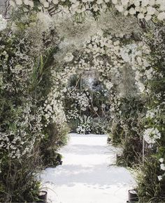 an outdoor wedding ceremony with white flowers and greenery on either side of the aisle