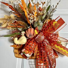 a wreath with fall leaves, pumpkins and gourds hanging on a door