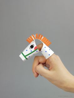 a hand holding a paper toy with a horse on it's head and an orange mane