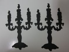 three metal candelabra shaped like candlesticks on a white table top