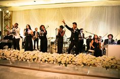 a group of people standing on top of a stage next to flowers and microphones