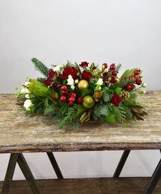 a wooden table topped with a bouquet of flowers and greenery on top of it