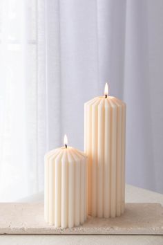 two white candles sitting on top of a table