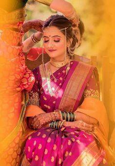 a woman in a pink and yellow sari sitting on the ground with her hands behind her head