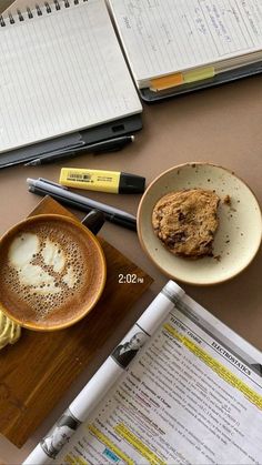 a table topped with two cups of coffee next to notebooks