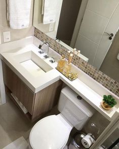 a white toilet sitting next to a sink in a bathroom under a mirror with towels hanging on the wall