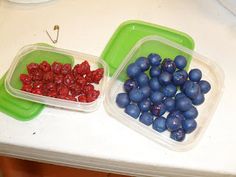 two plastic containers with blueberries and raspberries in them on a counter top