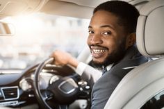 a man driving a car and smiling at the camera