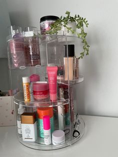 a clear shelf with various cosmetics and other items on it, sitting next to a white wall