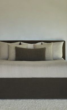 a bed with white and brown pillows on top of it