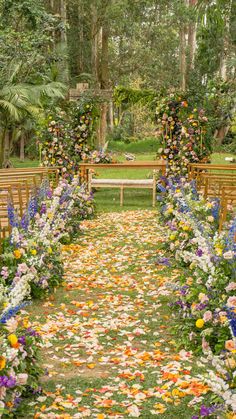 an outdoor wedding ceremony with flowers on the ground and wooden benches in the back yard