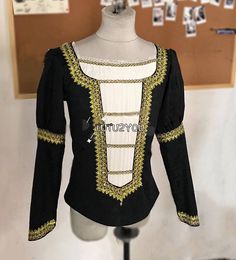 a mannequin wearing a black and white top with gold trims on it