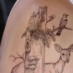 a deer and bird tattoo on the back of a woman's shoulder