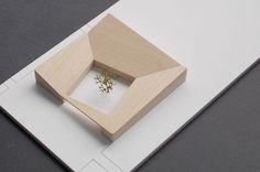 a small wooden object sitting on top of a white piece of paper with a tiny flower in it