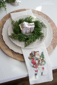 a christmas place setting with napkins and gingerbread house on the plate next to it