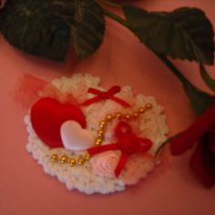 an ornament with two hearts on it next to a rose and some leaves