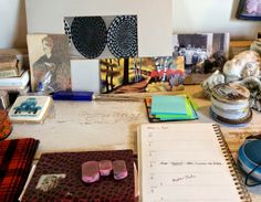 a cluttered desk with various items on it and pictures hanging above the table top