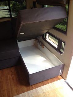 an open storage compartment in the back of a camper with wood flooring and windows