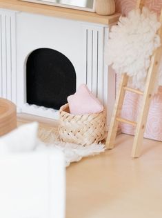 a doll house with a fireplace, ladder and basket on the floor next to it