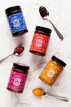 four jars of jam with spoons next to them