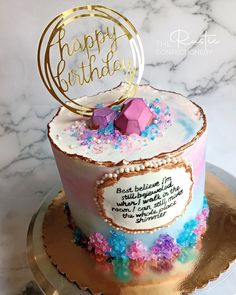 a birthday cake decorated with pink, blue and purple flowers on a gold platter