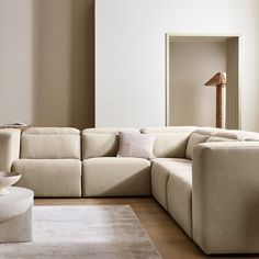 a living room with a large sectional couch and white rug on the floor in front of a mirror