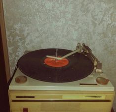 an old record player sitting on top of a wooden table next to a white wall