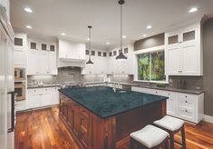 a large kitchen with white cabinets and green counter tops