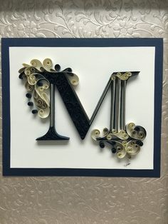 the letter m is made out of buttons and paper quillings on a white card